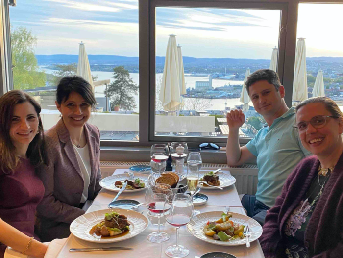 group of 4 persons sat at a dining table with a view towards Oslo
