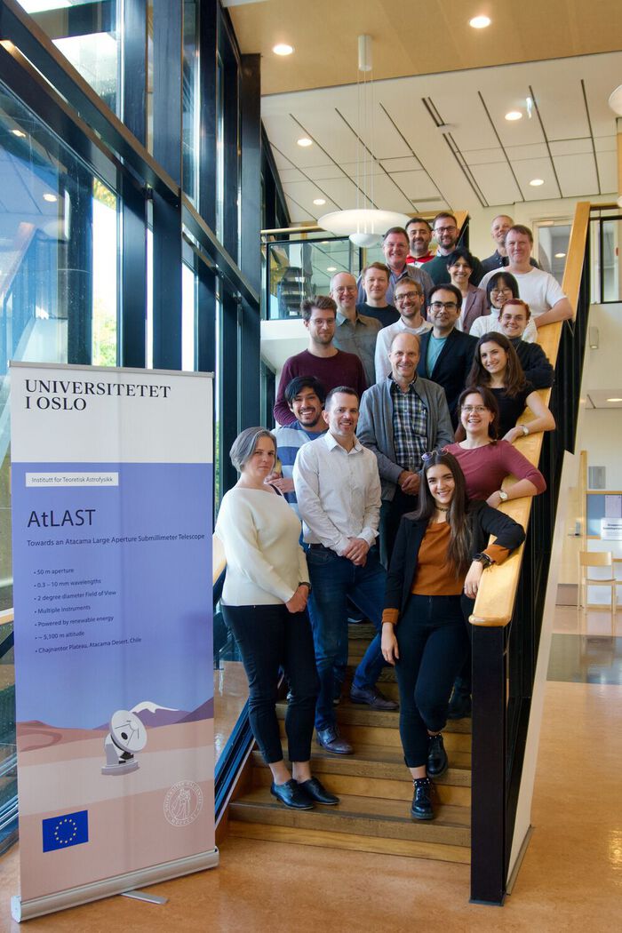 group photo of people standing on stairs, next to a roll-up