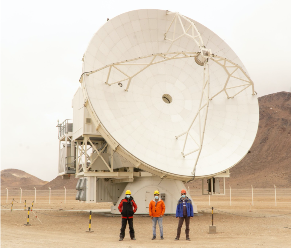 photo of three persons standing in front of a large radio antenna