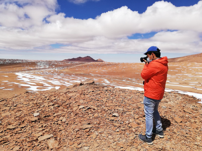 panoramic picture of a chilean desert with orange soil, blue sky with white clouds and some snow